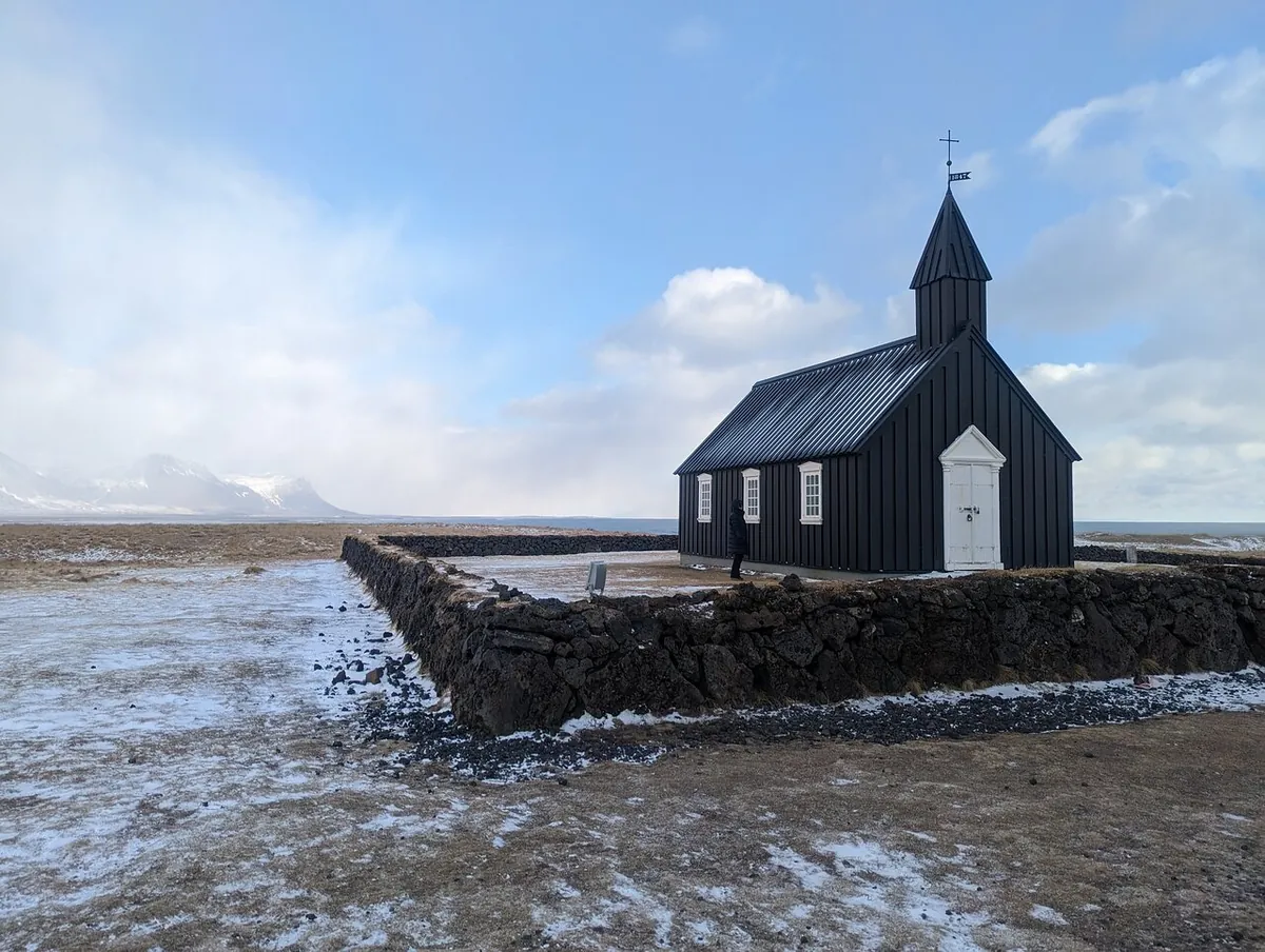 Die schwarze Kirche in Budir, von Schnee umgeben, unter grauem Winterhimmel